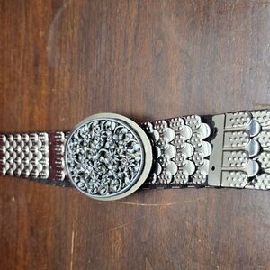 metal stretch belt with a large, ornate oval floral buckle